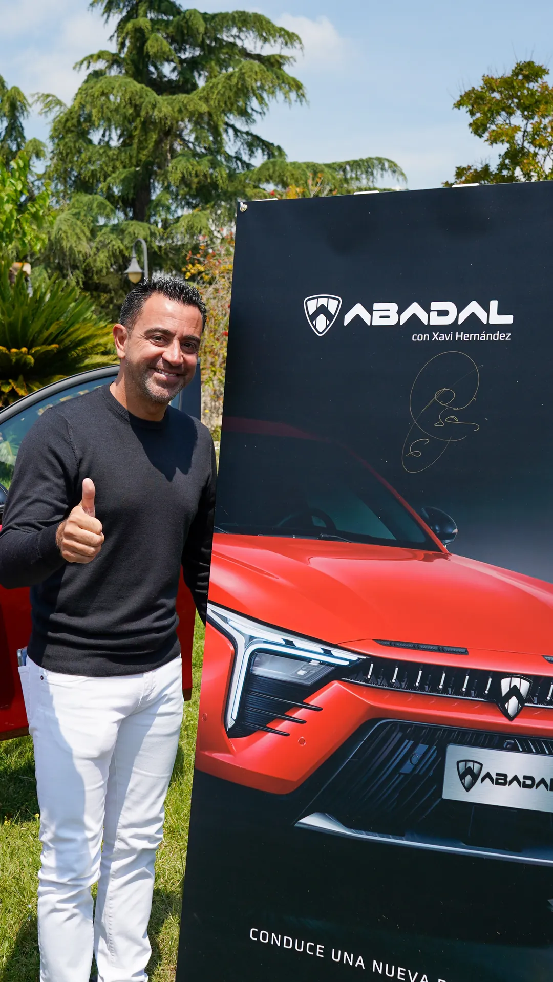 Xavi Hernández junto al cartel firmado de ABADAL