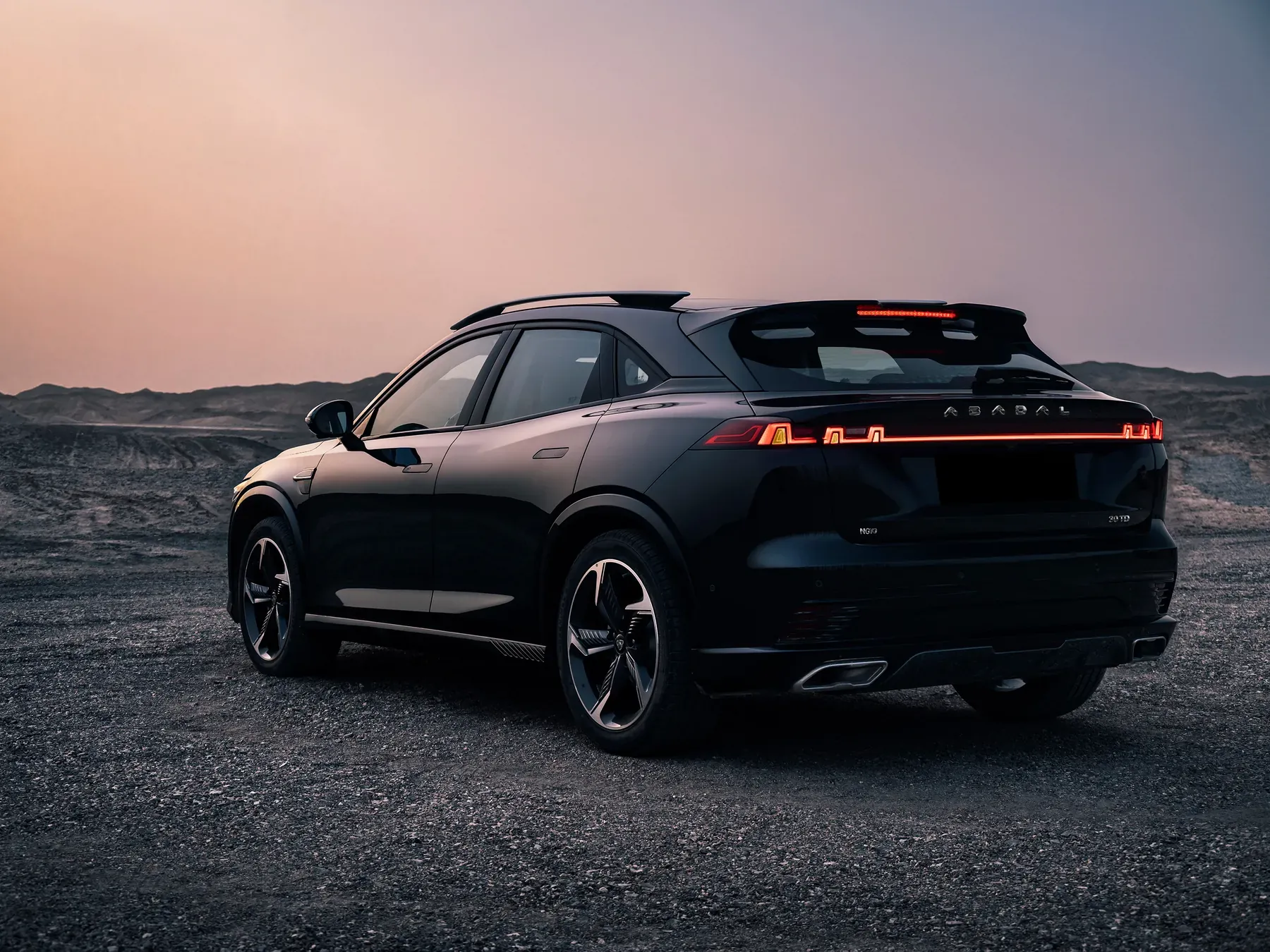Rear three-quarter view of the black ABADAL NOVO at dusk with its lights on